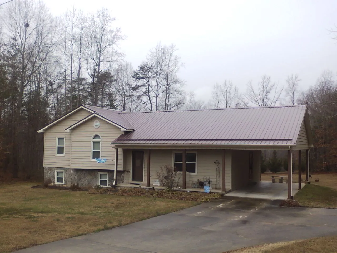 Burgundy metal roof on a tan split level home with an attached carport in Danville